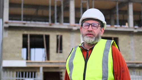 Close up caucasian male engineer builder in white helmet with vest in glasses on street