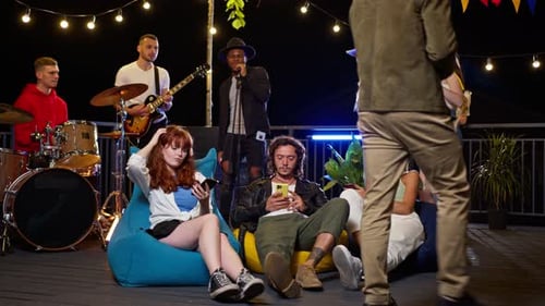 Friends enjoying live music on rooftop terrace at night
