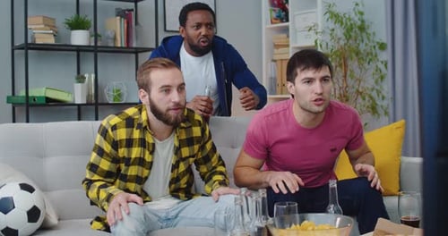 Three Friends Excitedly Watch Sports Game Together