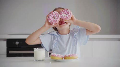 the Happy Little Girl is Playing with Donuts the Beautiful Girl is Playing with Donuts in the