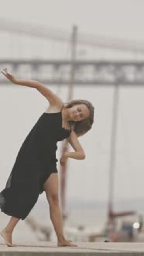 A Woman in Black Dress Dancing on the Pier in