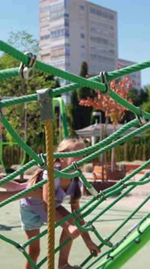 Young Girl Climbing on Rope Structure at Playground