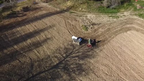 crawler tractor with seeder working the ground in the field, aerial shhot moving away