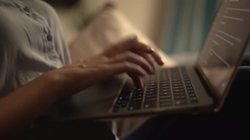 Eine Nahaufnahme von Händen, die aktiv auf einem Laptop tippen, während sie von zu Hause aus in einer gemütlichen Umgebung arbeiten