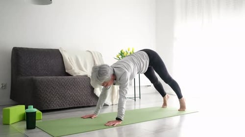 Senior Woman Does Yoga on Mat at Home