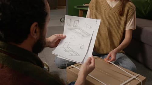 Un homme étudie les instructions de montage tout en ouvrant une boîte plate avec sa femme