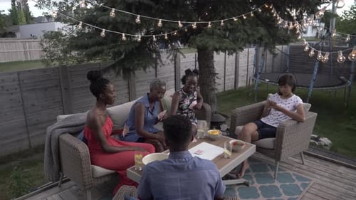 Friends Playing Cards on Deck with String Lights