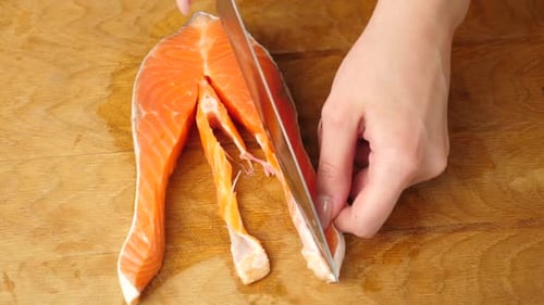 Cutting a Salmon Steak on a Wood Board