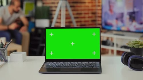 Laptop Display Showing Isolated Green Screen on Empty Table