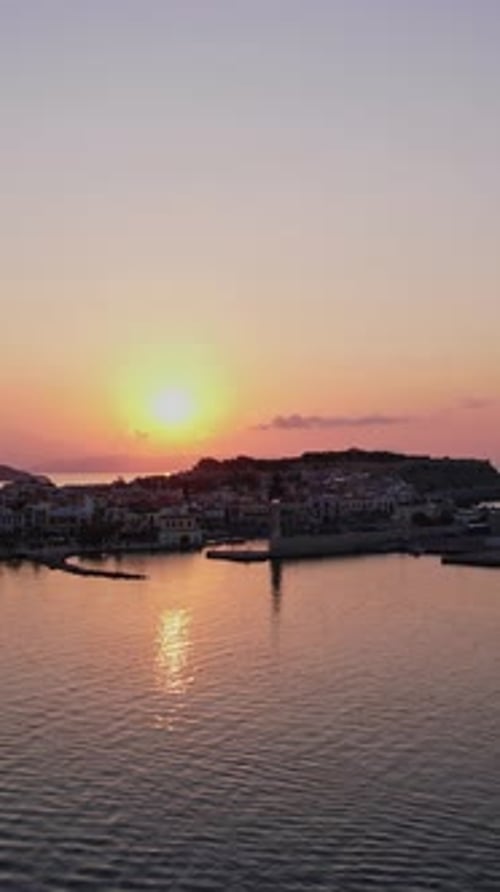 Le soleil se couche sur un port tranquille, projetant des teintes chaudes sur l'eau
