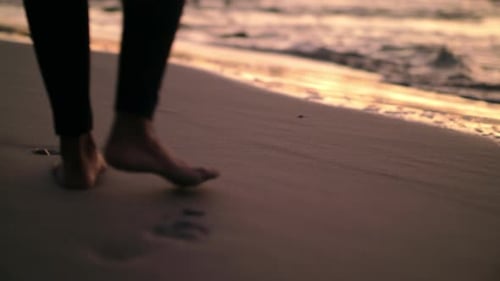 4K video footage of a young couple enjoying a romantic walk on a beach together at sunset