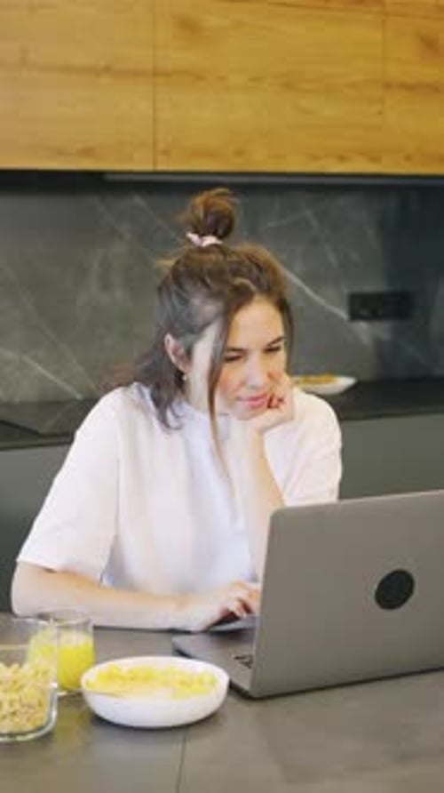 Woman Working on Laptop at Kitchen Table
