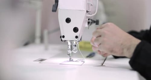 Closeup of hands threading an industrial sewing machine