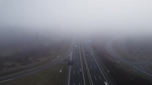 Backwards aerial flight in cloudy weather tilting down on German highway with driving white cars in
