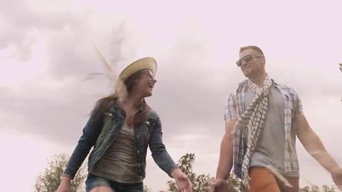 Happy caucasian couple piggybacking running through a windy field in autumn