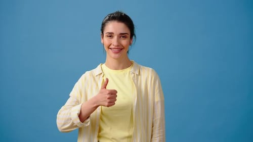 Smiling Woman Gives Thumbs Up on Blue Background