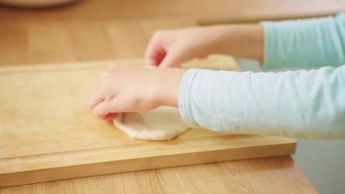 Close up of young cute girl doing homemade bakery alone in the kitchen.