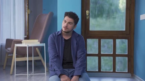 Young Man Sitting and Pondering Indoors