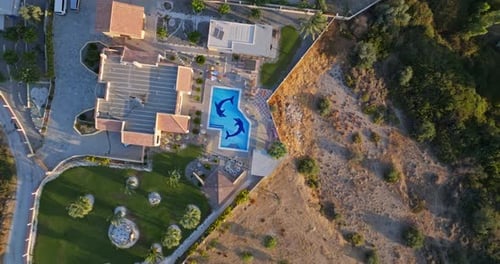 Screwdriver drone shot rising above a pool, at a villa in Greece, sunny morning
