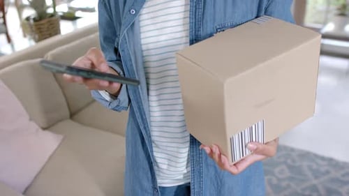 Woman Holds Package with Phone Indoors