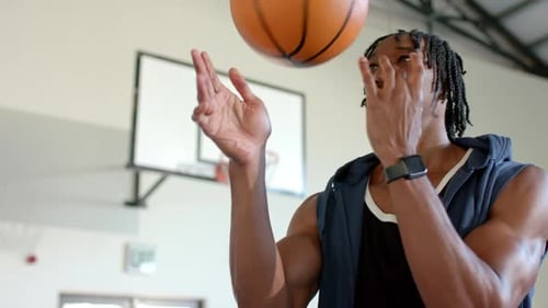Spinning basketball on finger, man practicing skills in indoor gymnasium