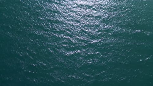Aerial view of dark ocean surface with shimmering waves under daylight. Abstract natural background