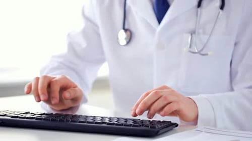Nahaufnahme männlicher Arzthände, die auf den Tastaturarmen tippen