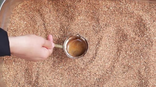 Blick von oben auf die Zubereitung von traditionellem türkischen Kaffee auf Sand