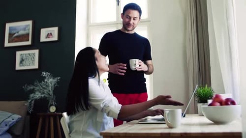Smiling Couple Using Laptop in Bright Home