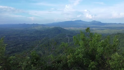 Aerial view of high voltage pylons on green hills, consisting of steel frames to support or carry ca