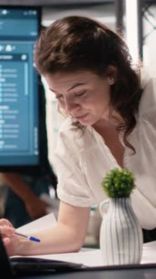 Vertical Video Woman Real Estate Engineer Reviews City Planning Blueprints on Laptop