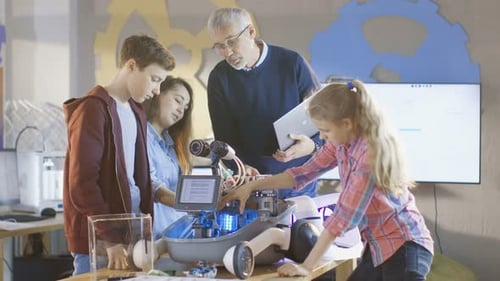 Un enseignant et ses élèves travaillent sur un robot programmable avec éclairage LED pour la classe de sciences scolaire P