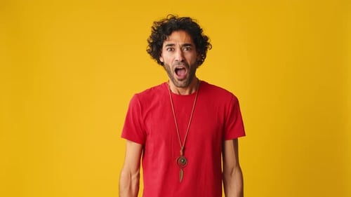 Wonder man put his hands on his head looking at camera isolated on yellow background in studio