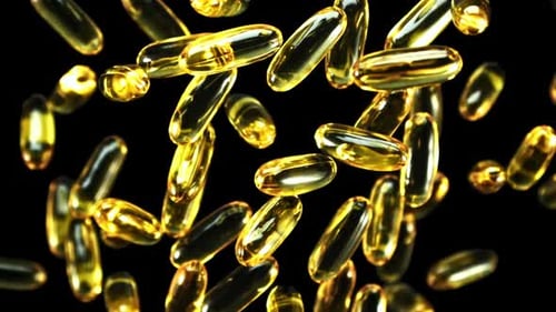 Floating Golden Vitamin Capsules on Black Background