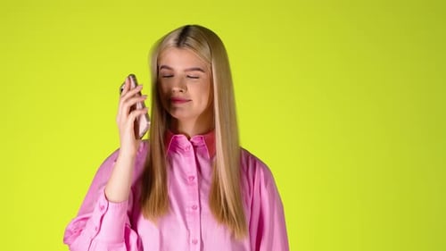 Young Blonde Woman In Pink Shirt Talking On Phone Then Hang Up Against Green Background, Studio Shot