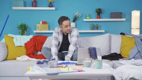 Man Lies on Sofa in Messy Living Room