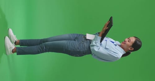 Side View Of Full Body Asian Business Woman Using Tablet On Green Screen Background In The Studio