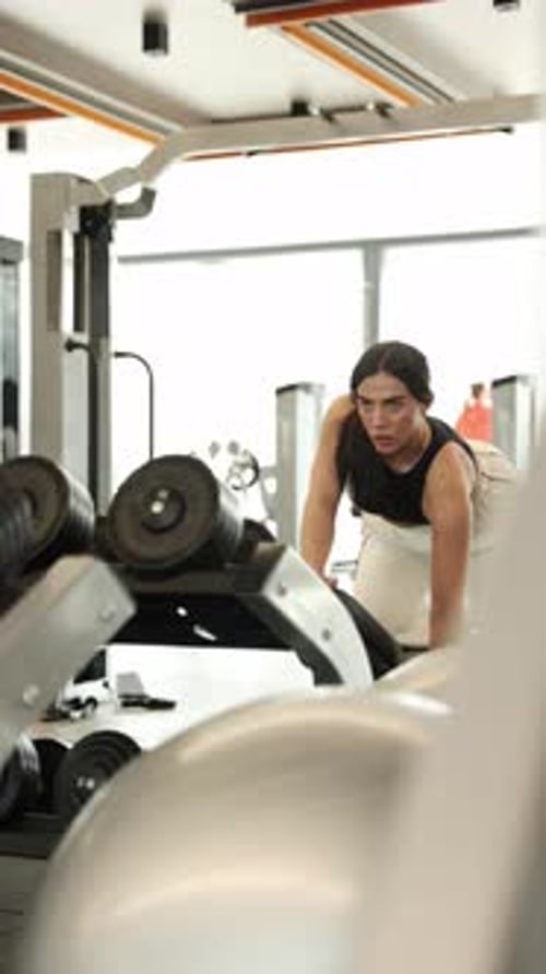 Focused Woman Working Out in the Gym with Weights in a Modern Fitness Center Environment