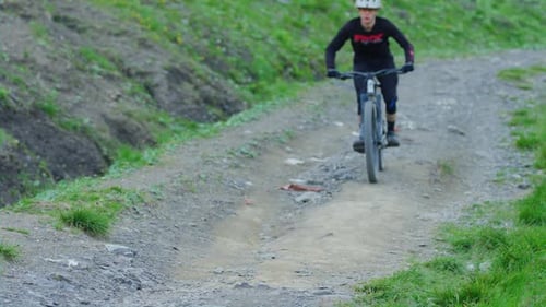 A mountain biker is blasting down a hill in slow motion
