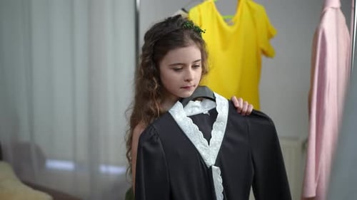 Experimentando roupas para uma garotinha Uma pequena fashionista experimenta um vestido enquanto está na frente de