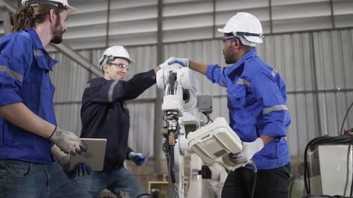 Blue collar workers are working at machine shop with welding robot arm.