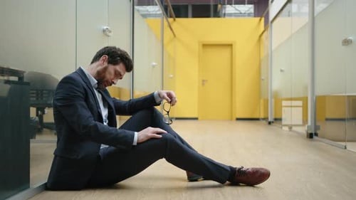 Nahaufnahme eines kaukasischen Finanzmaklers in formellem Anzug, der im leeren Korridor sitzt