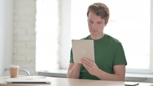 Young Adult Using Tablet at Desk in Office