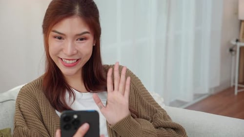 Smiling Woman Using Mobile Phone Indoors on Couch
