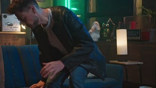 Man Sits On Couch Looking At His Phone