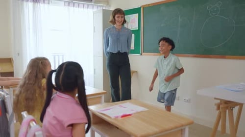 African American boy student dancing in front of classroom at school.