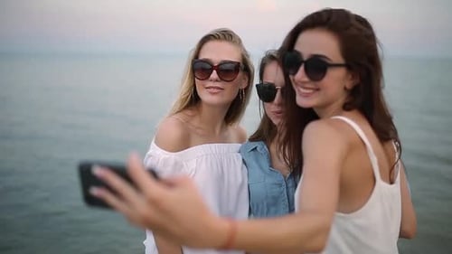 Three Young Women Taking a Selfie on the Beach with a Sea View Friends are Smiling Looking at the