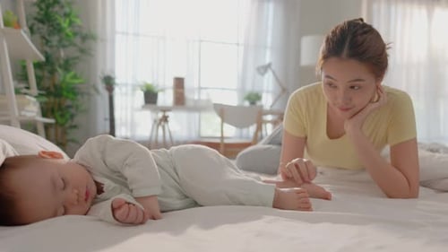 Woman Watches Sleeping Baby Lying on Bed