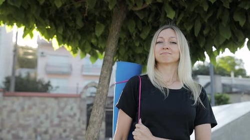 Blonde Woman with Yoga Mat in Urban Setting