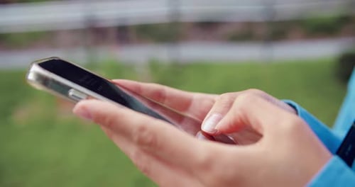 Woman's Hands Using Smartphone for Communication Outdoors